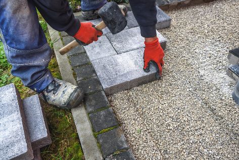 Concrete Pavers working on the sidewalk for a commercial property. In this image you see a Brooklyn concrete contractor working with concrete pavers. The image was taken in January 2022